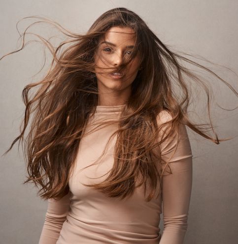 Portrait of a beautiful young woman posing with the wind in her hair in studio.